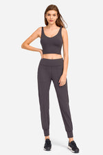 Model wearing a deep V-neck crop sports bra and matching joggers in a sleek dark gray color, showcasing sporty style and comfort.