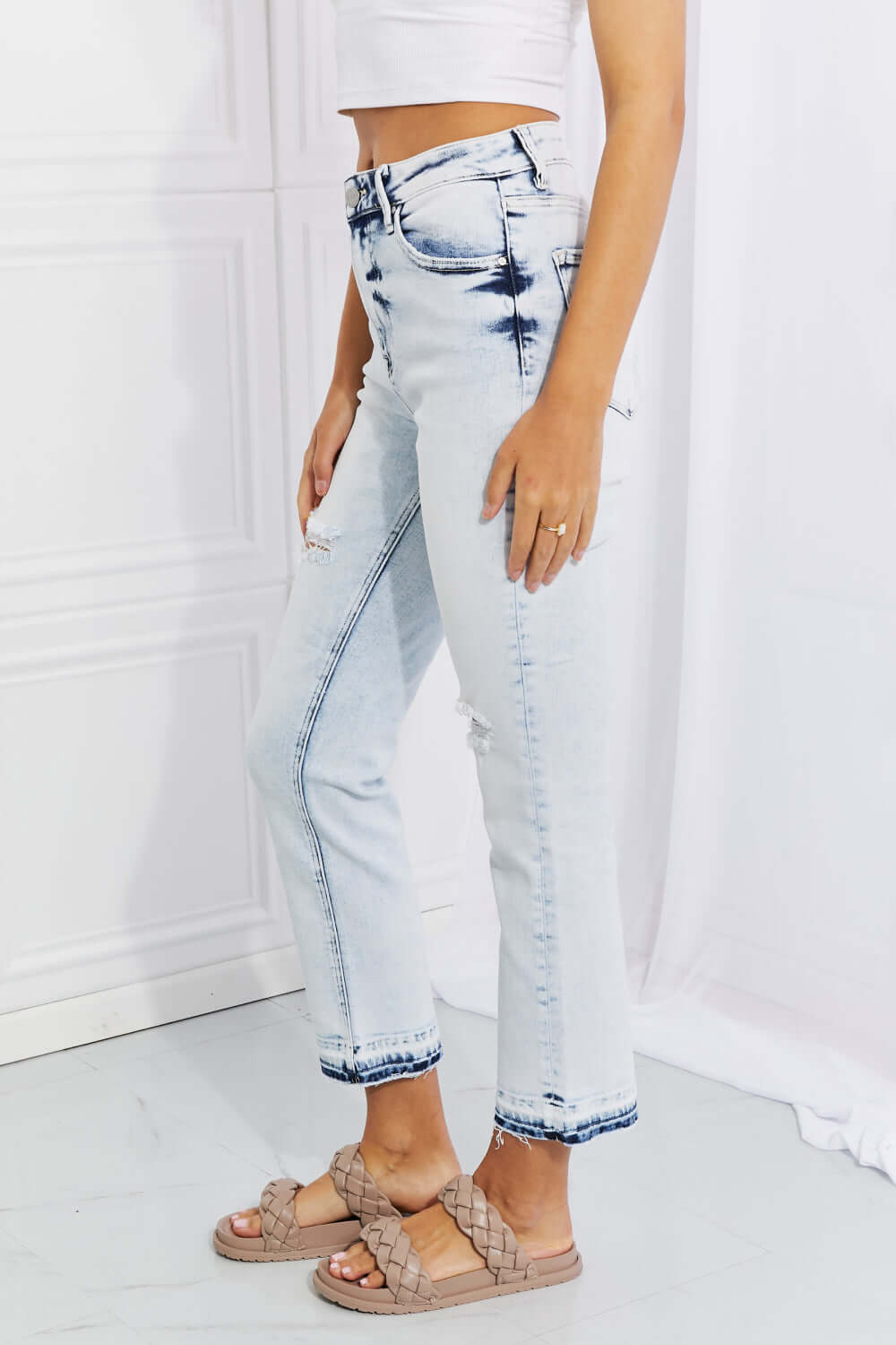 Woman wearing Camille Acid Wash Crop Straight Jeans by Risen Jeans, showcasing trendy distressed details and a flattering straight cut.