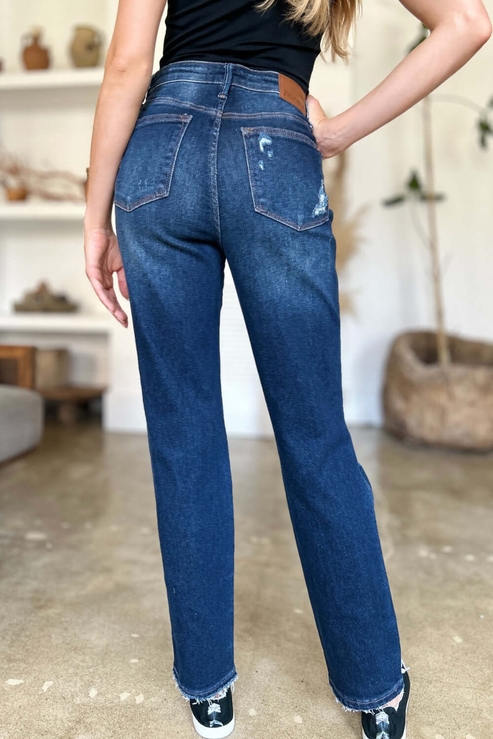 Woman wearing High Waist Rigid Magic Heavy Destroy Straight Judy Blue Jeans, showcasing back view in a casual indoor setting