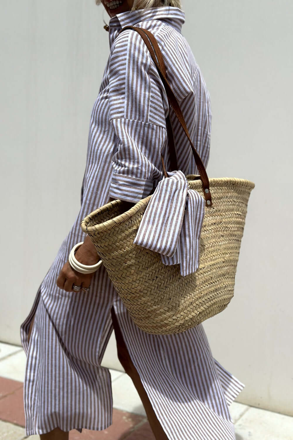 Woman wearing Bella Road Tied Button Up Three-Quarter Sleeve Dress with a woven straw bag