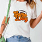 Woman wearing GAME DAY round neck short sleeve t-shirt, white with orange text, paired with distressed jeans and green shoulder bag.