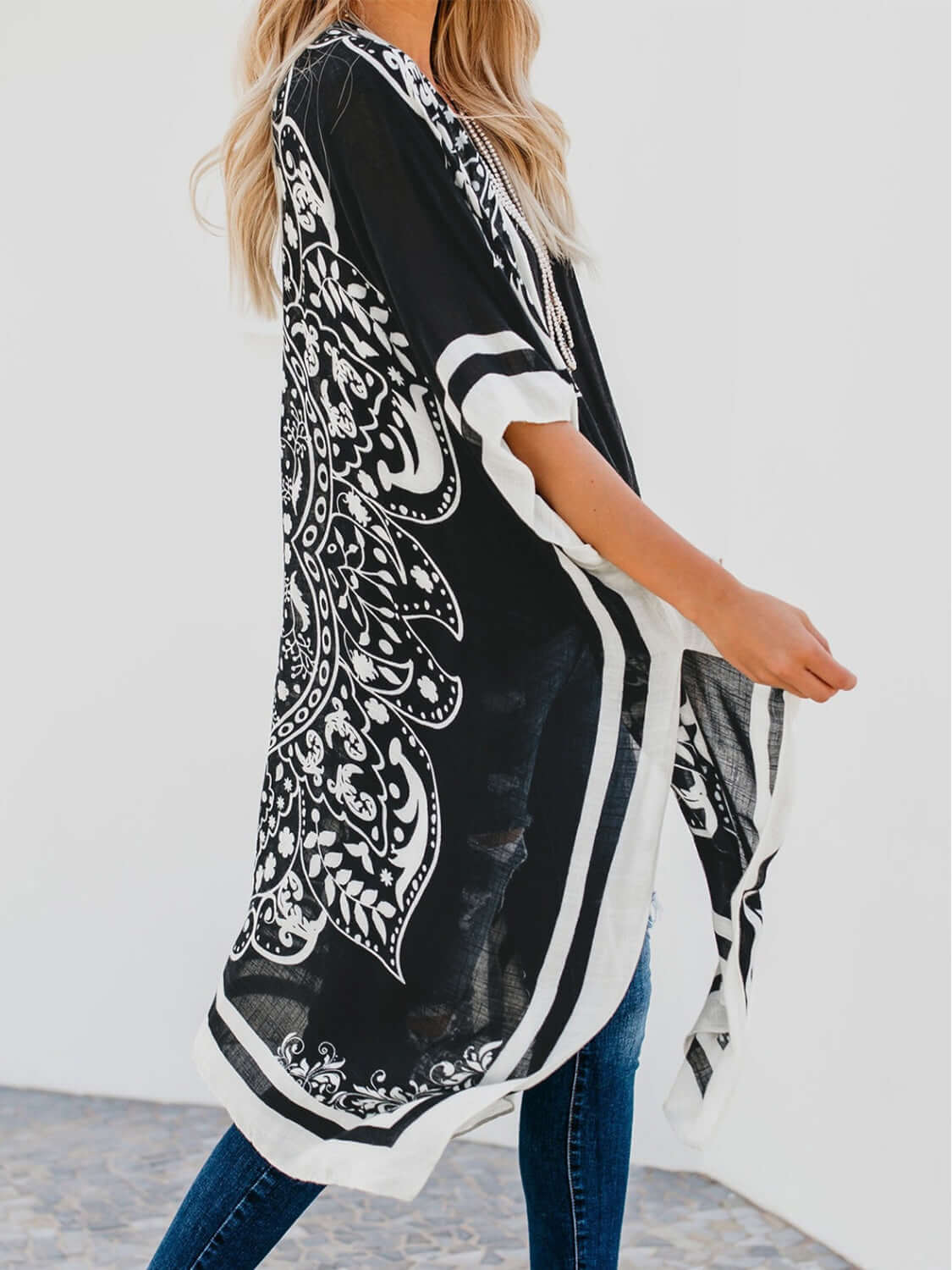 Woman in a stylish black and white printed open front cover-up, perfect for beach outings.