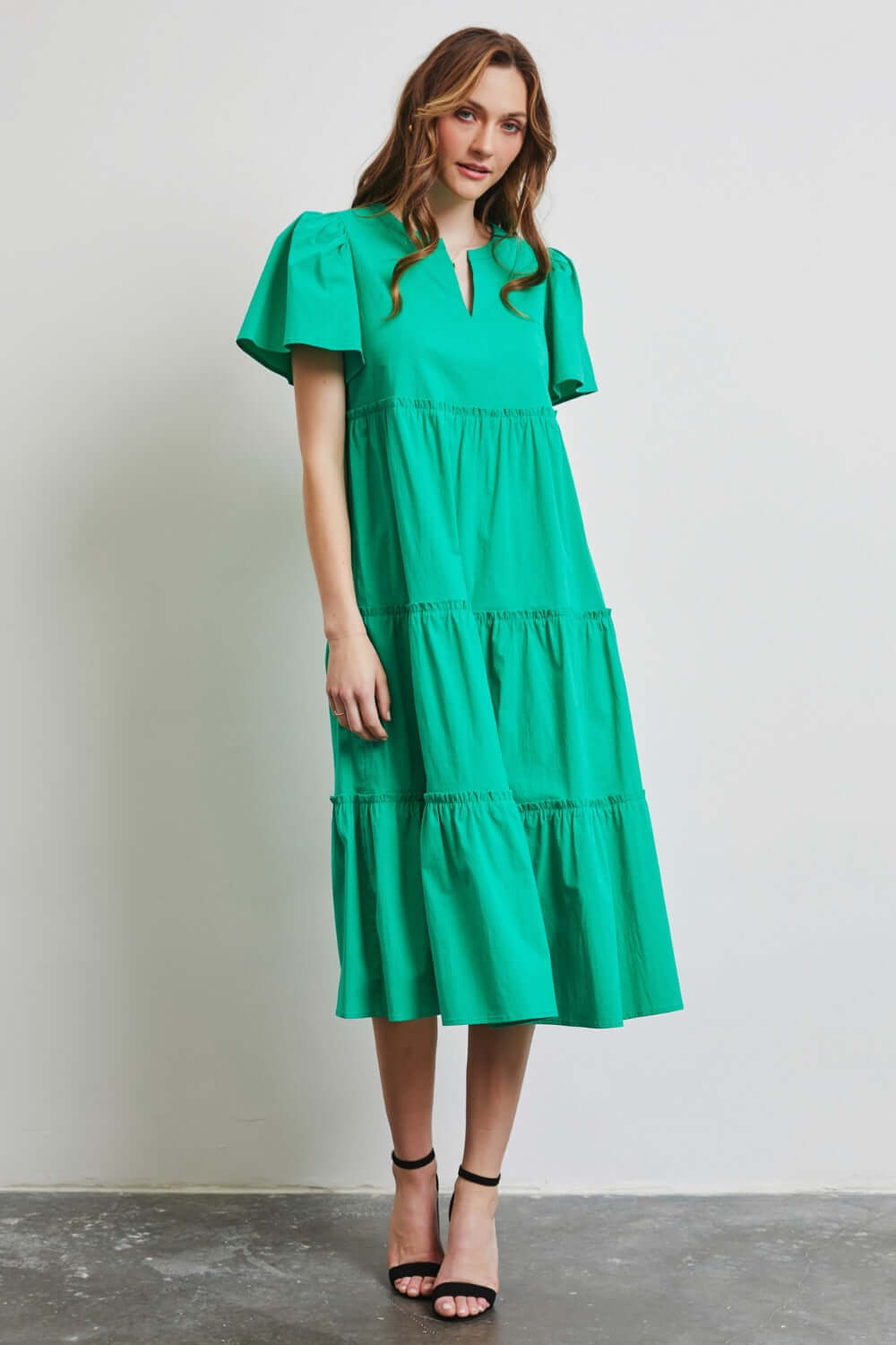 Woman wearing HEYSON green cotton poplin ruffled tiered midi dress, perfect for a stylish and comfortable warm weather outfit.