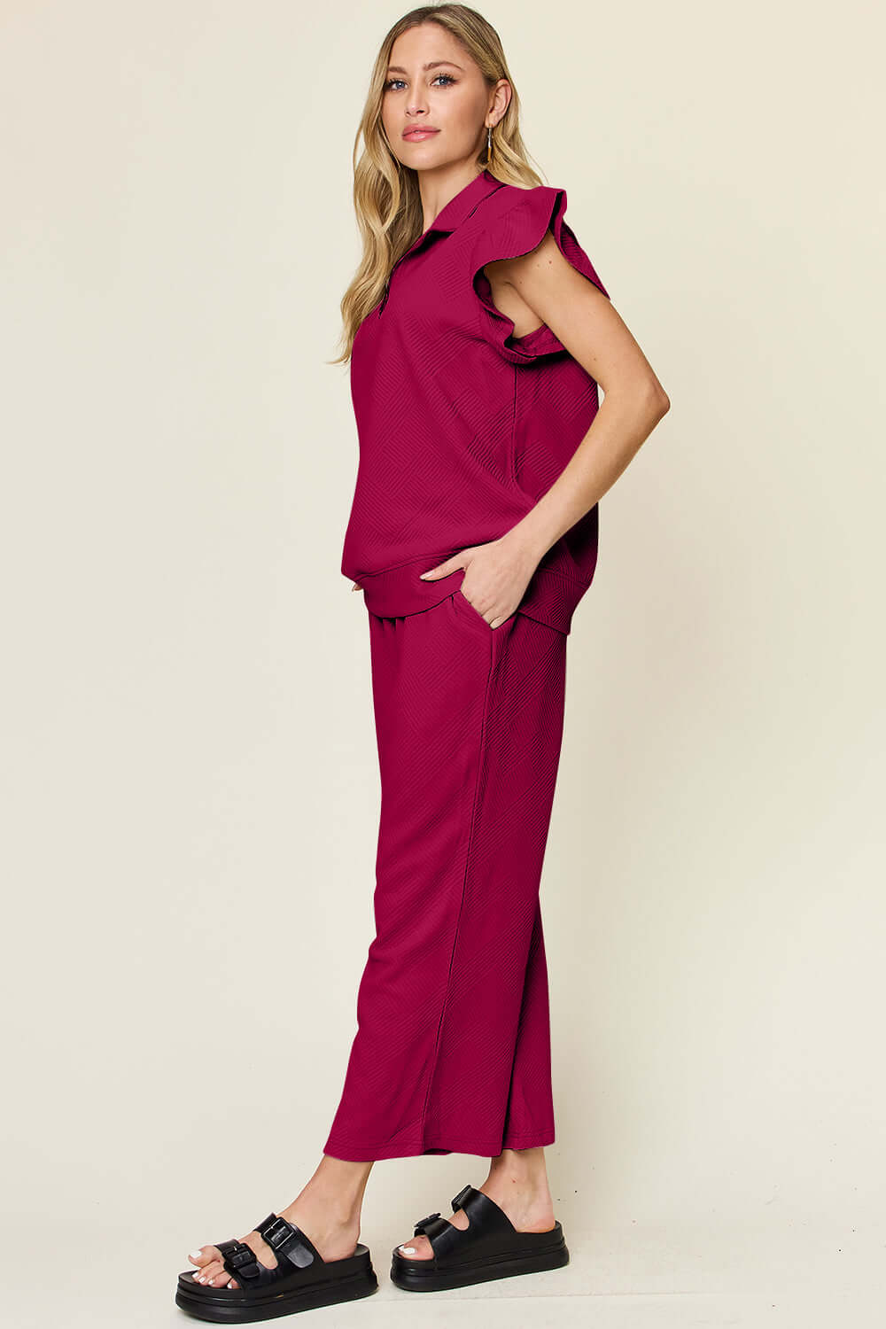 Woman wearing a Texture Ruffle Short Sleeve Top and Drawstring Wide Leg Pants Set in deep red, featuring pockets and a slightly stretchy material.