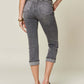 Woman wearing Button Fly High Waist Cuffed Capris in gray by Judy Blue Jeans, showcasing back view with chic casual style.