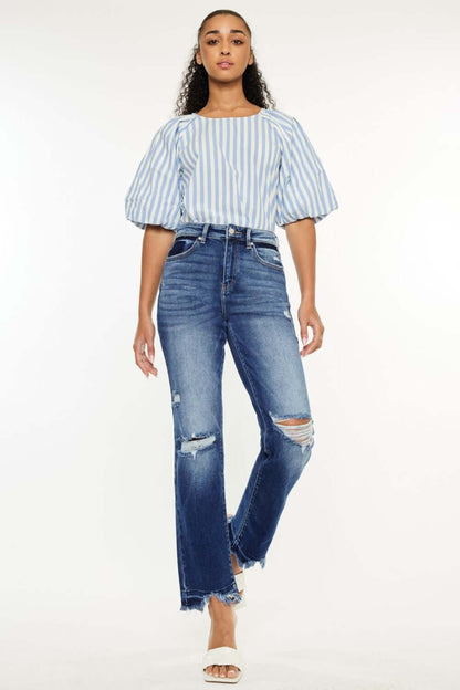 Woman wearing Kancan high-rise distressed slim straight jeans with a stylish striped top, showcasing trendy casual fashion.