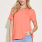 Woman wearing bamboo V-neck high-low T-shirt in coral, paired with light blue jeans.