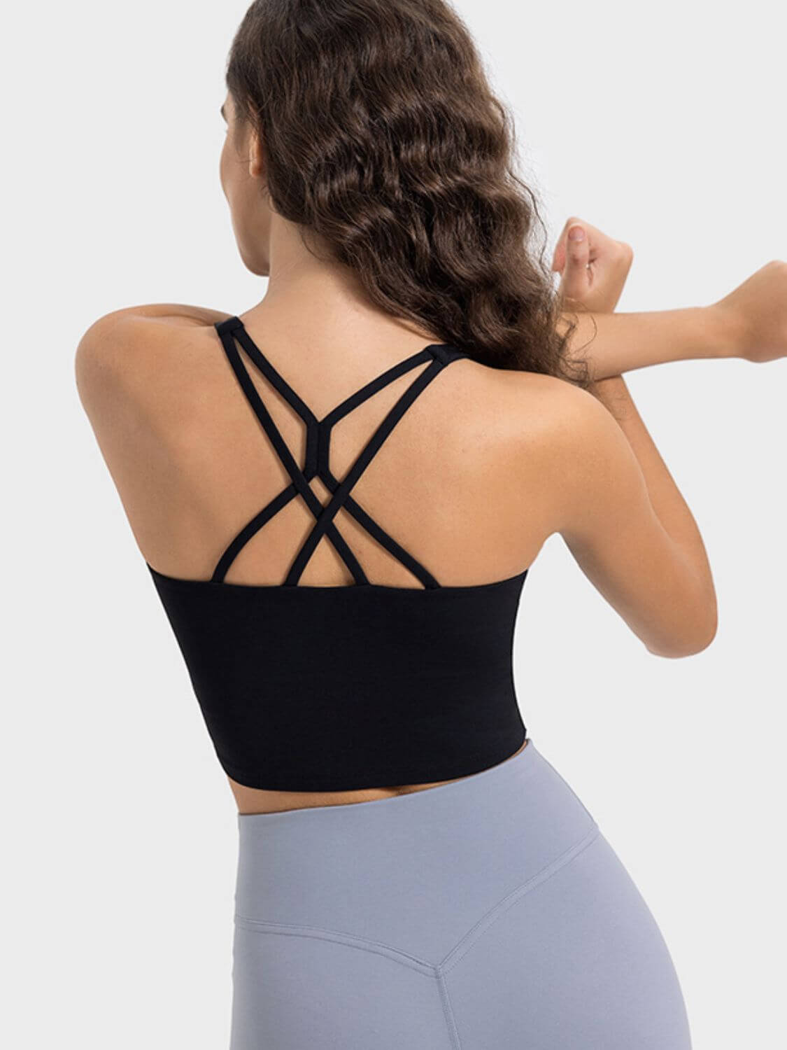 Model showcasing the stylish crisscross back of the Millennia Active Tank in black, perfect for workouts and comfort.