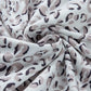 Close-up of a white fabric with a bold leopard print pattern, showcasing the stylish design of the Bella Road Drawstring Set.