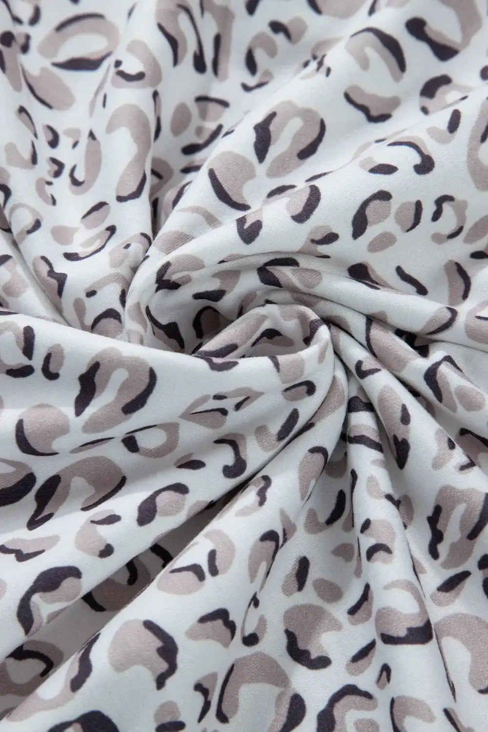 Close-up of a white fabric with a bold leopard print pattern, showcasing the stylish design of the Bella Road Drawstring Set.