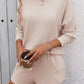 Woman wearing Double Take Round Neck Long Sleeve Top and Shorts Set, holding a coffee cup, trendy casual outfit for lounging or outings.