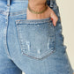 Woman wearing high waist Judy Blue Jeans denim shorts with rhinestone decor on back pocket, showcasing stylish and glamorous design.