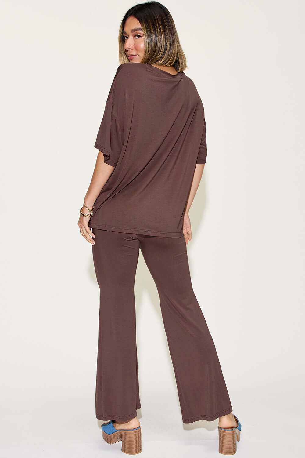 Woman wearing a brown bamboo drop shoulder T-shirt and flare pants set, viewed from the back, showcasing the two-piece outfit's relaxed fit and basic style.