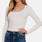 Woman wearing white scoop neck long sleeve t-shirt with blue jeans, showcasing a stylish and versatile wardrobe essential.