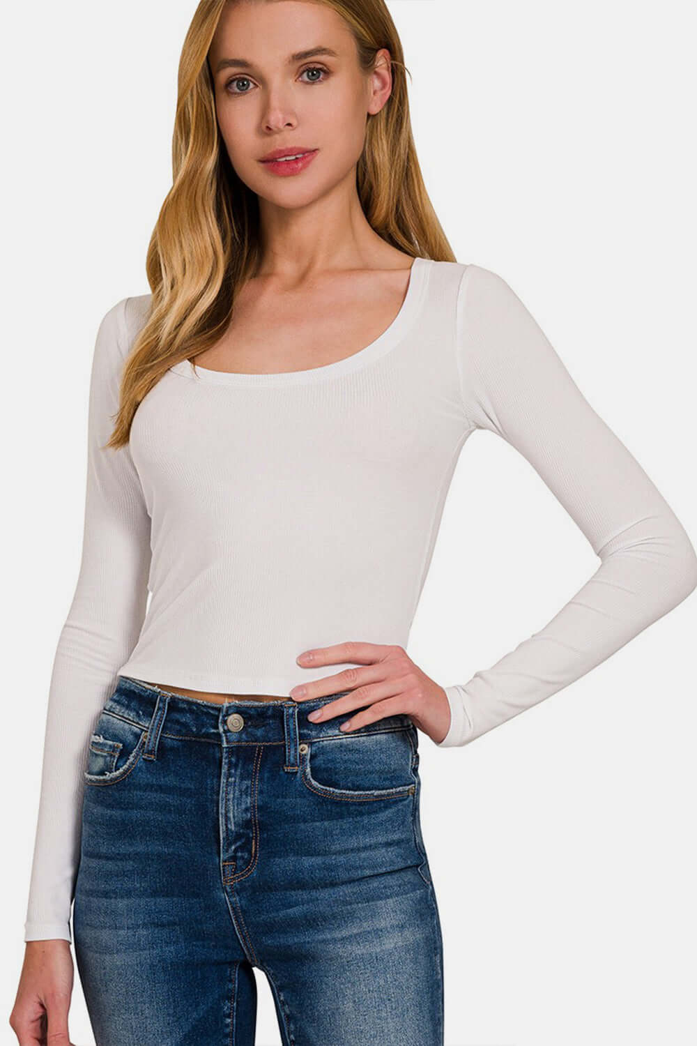 Woman wearing white scoop neck long sleeve t-shirt with blue jeans, showcasing a stylish and versatile wardrobe essential.