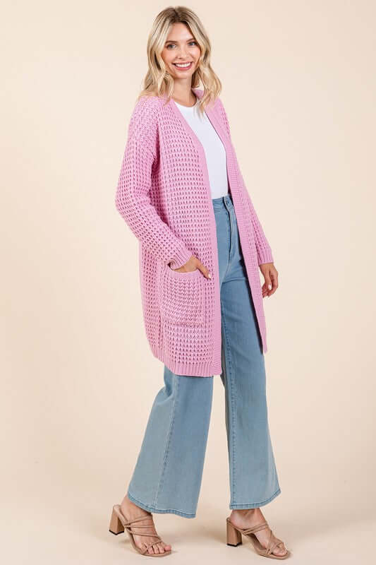 Stylish woman in a pink open front longline cardigan paired with flared jeans, perfect for layering and versatile fashion.