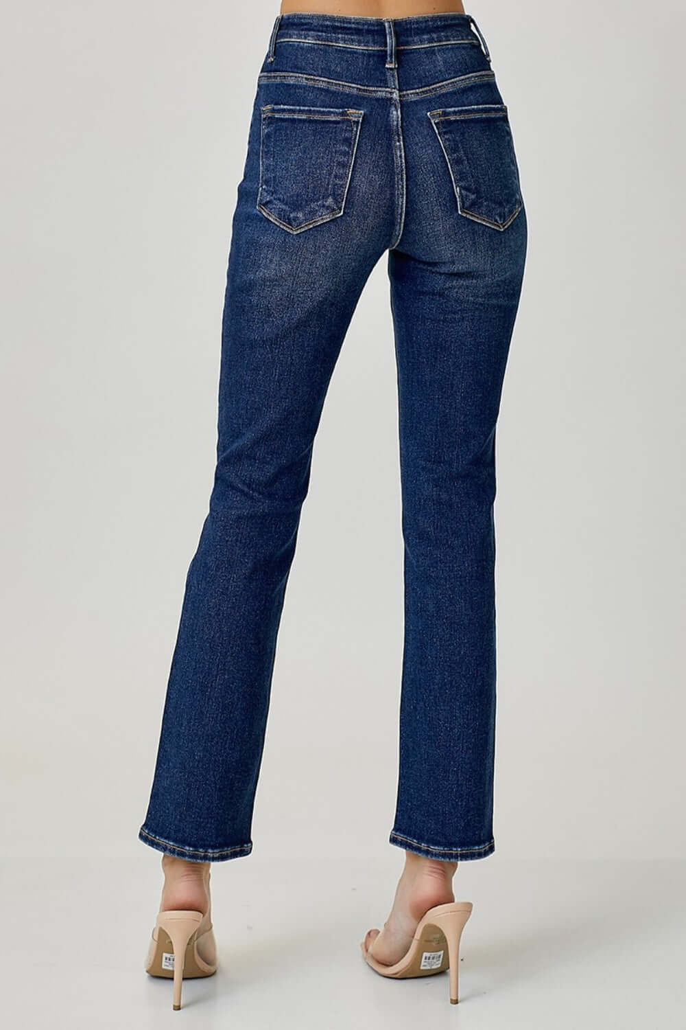 Back view of high waist straight jeans by Risen Jeans, featuring a classic straight leg fit and back pockets, paired with nude heels.