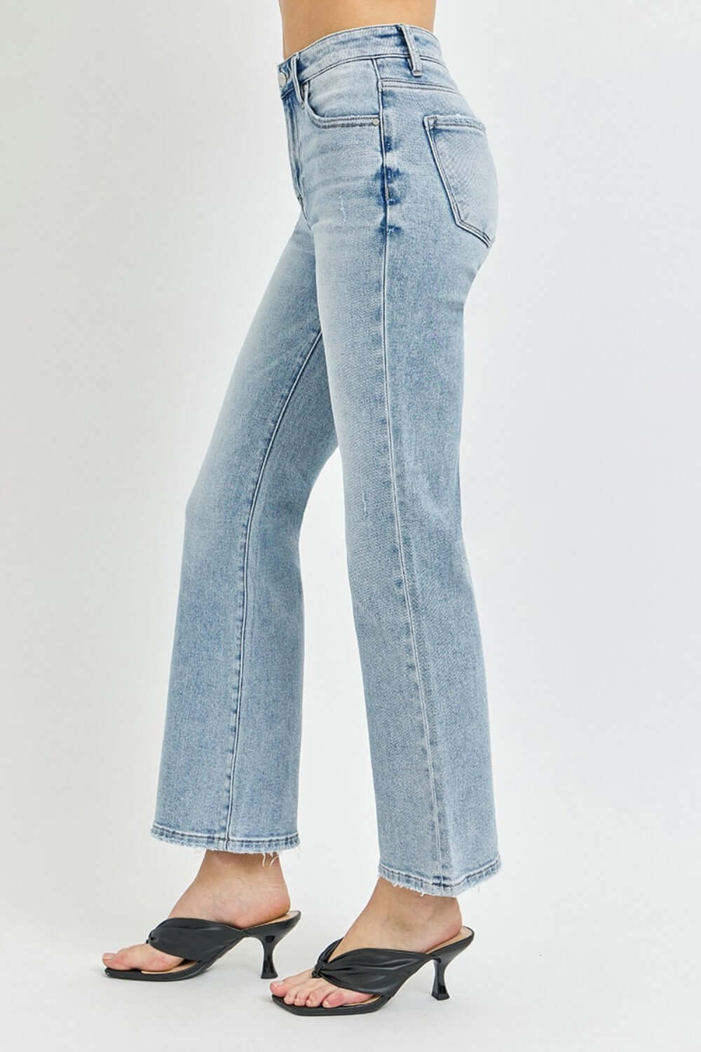 Woman wearing RISEN Full Size High Rise Ankle Flare Jeans in light denim, showcasing the high-waisted fit and trendy flared hem.