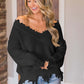 Woman wearing Bella Road black frayed hem dropped shoulder sweater with jeans, exuding playful and stylish vibes.