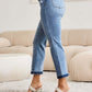 Woman wearing Judy Blue release hem cropped bootcut jeans with white heels, showcasing the trendy and versatile denim style.