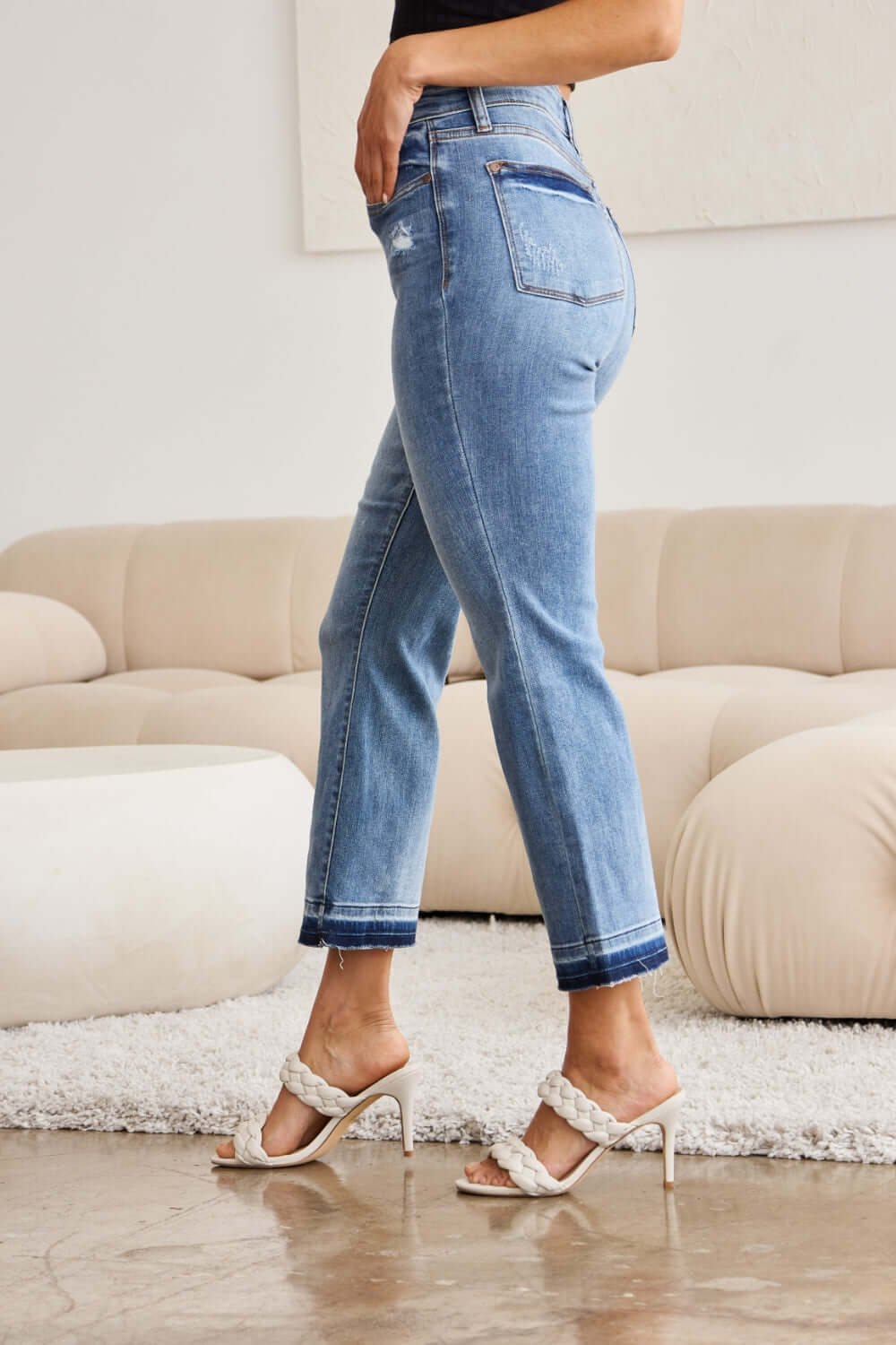 Woman wearing Judy Blue release hem cropped bootcut jeans with white heels, showcasing the trendy and versatile denim style.