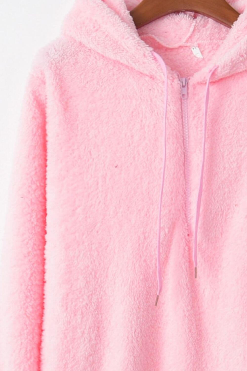 Soft pink quarter-zip teddy hoodie with drawstring and cozy texture, perfect for casual wear.