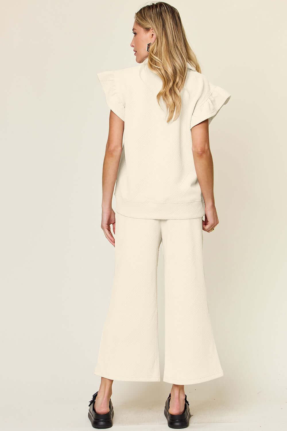 Woman wearing a cream Texture Ruffle Short Sleeve Top and Drawstring Wide Leg Pants Set with black shoes, viewed from the back.