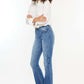 Woman wearing Kancan High Rise Frayed Hem Jeans, medium stone wash denim, classic 5-pocket style, and raw hem for casual outings.