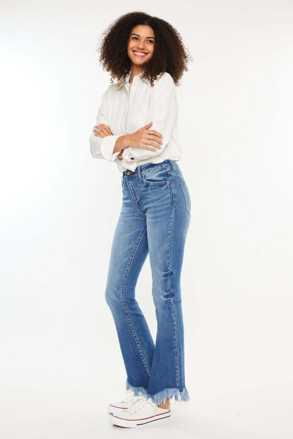 Woman wearing Kancan High Rise Frayed Hem Jeans, medium stone wash denim, classic 5-pocket style, and raw hem for casual outings.