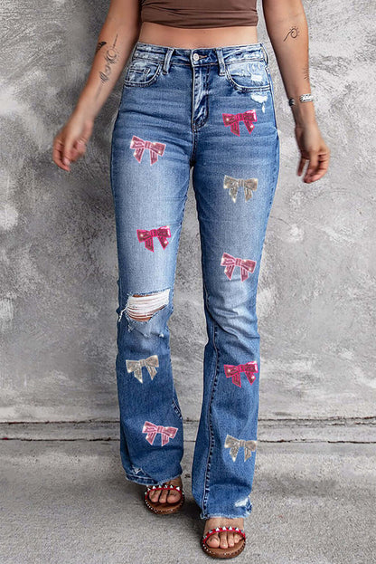 Bella Road Sequin Bow Distressed Bootcut Jeans worn by model with distressed details and multicolor sequin bows against gray background