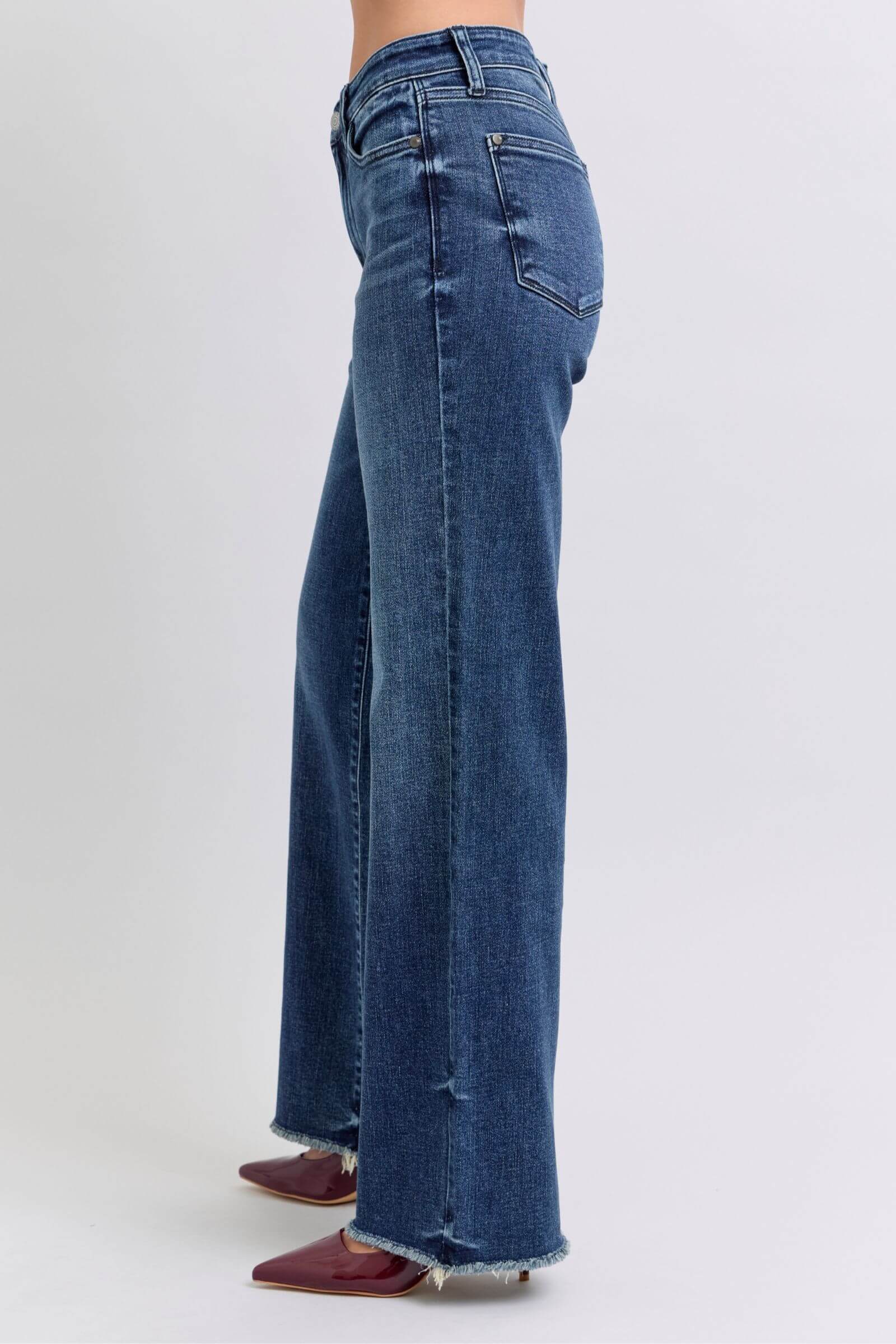 Side view of Judy Blue full-size raw hem mid-rise jeans showcasing a frayed edge and stylish fit.