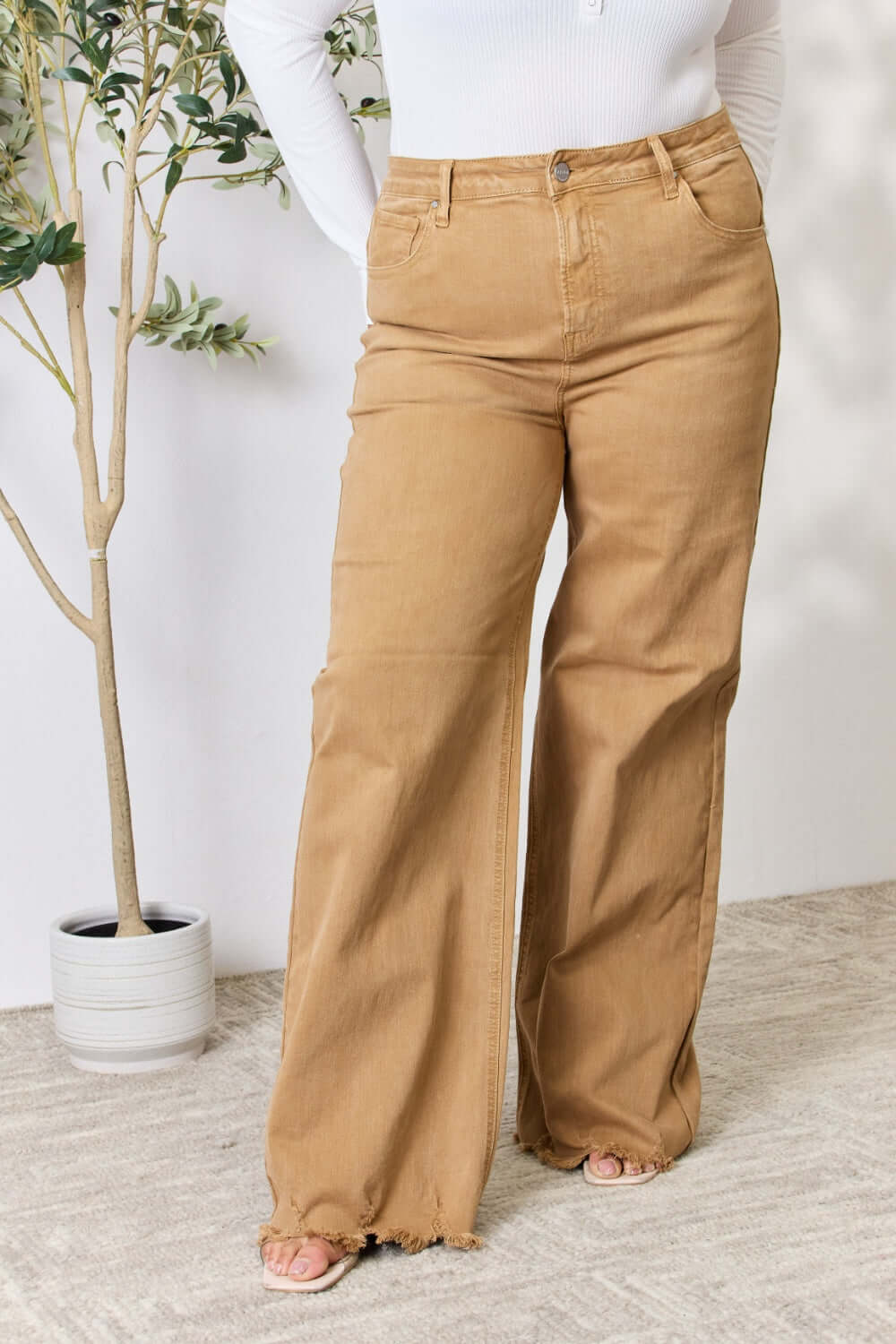 Woman wearing Risen Jeans Fringe Hem Wide Leg Jeans, showcasing high-waisted fit and trendy wide-leg design.