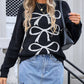 Woman wearing Angel Wings Bow Graphic Round Neck Long Sleeve Sweater paired with denim skirt, accessorized with sunglasses and handbag.