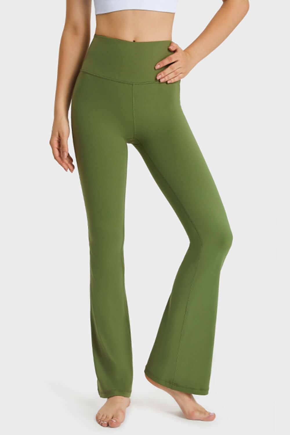 Model wearing Millennia Elastic Waist Flare Yoga Pants in green, showcasing comfort and style for yoga and workouts.