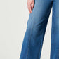 Woman wearing chic wide leg long jeans in solid blue denim with moderate stretch, ideal for a casual yet stylish look.