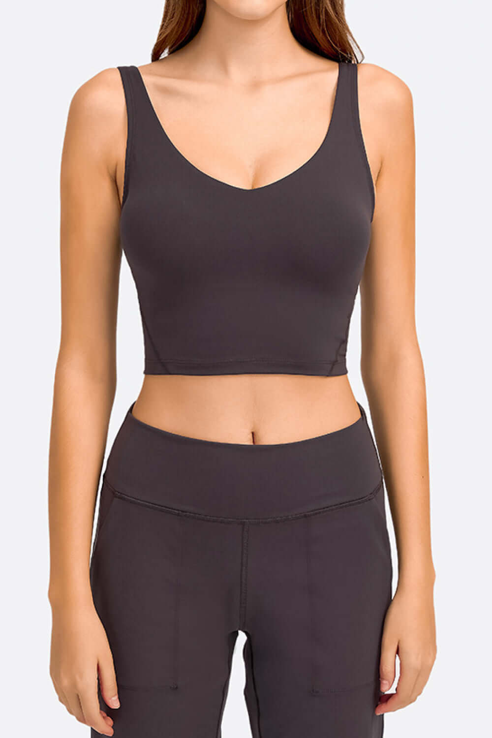 Model wearing the Millennia Deep V-Neck Crop Sports Bra in dark gray, showcasing comfort and style for active wear.