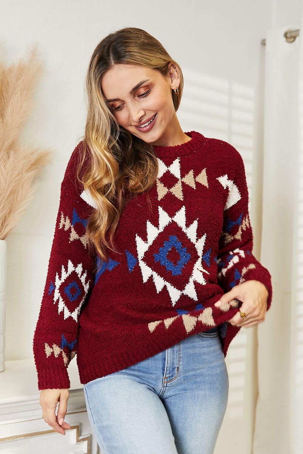 Woman wearing a red HEYSON Aztec sweater with geometric patterns, showcasing cozy and stylish charm.