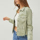 Model showcasing a stylish cropped denim jacket with raw hem in light green, paired with a white top and jeans.