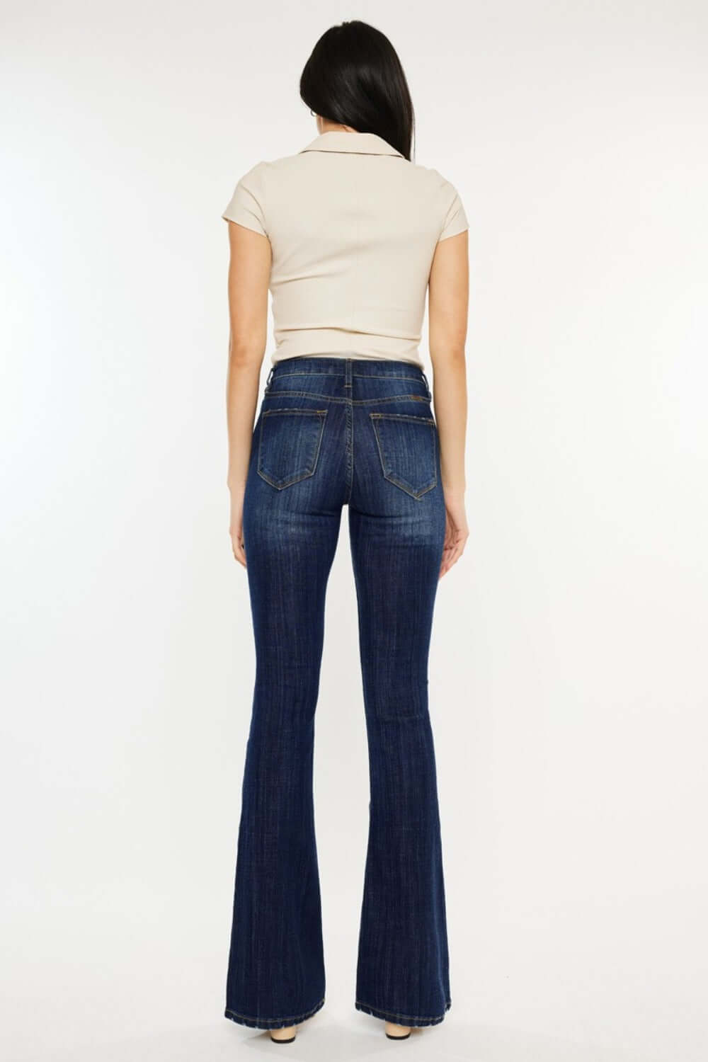 Woman wearing Kancan mid-rise slim flare jeans in dark stone wash, showcasing stylish back view and flattering silhouette.