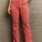 Woman wearing Bailey High Waist Side Slit Flare Jeans in coral, showcasing trendy side slits and a flattering fit. Risen Jeans.