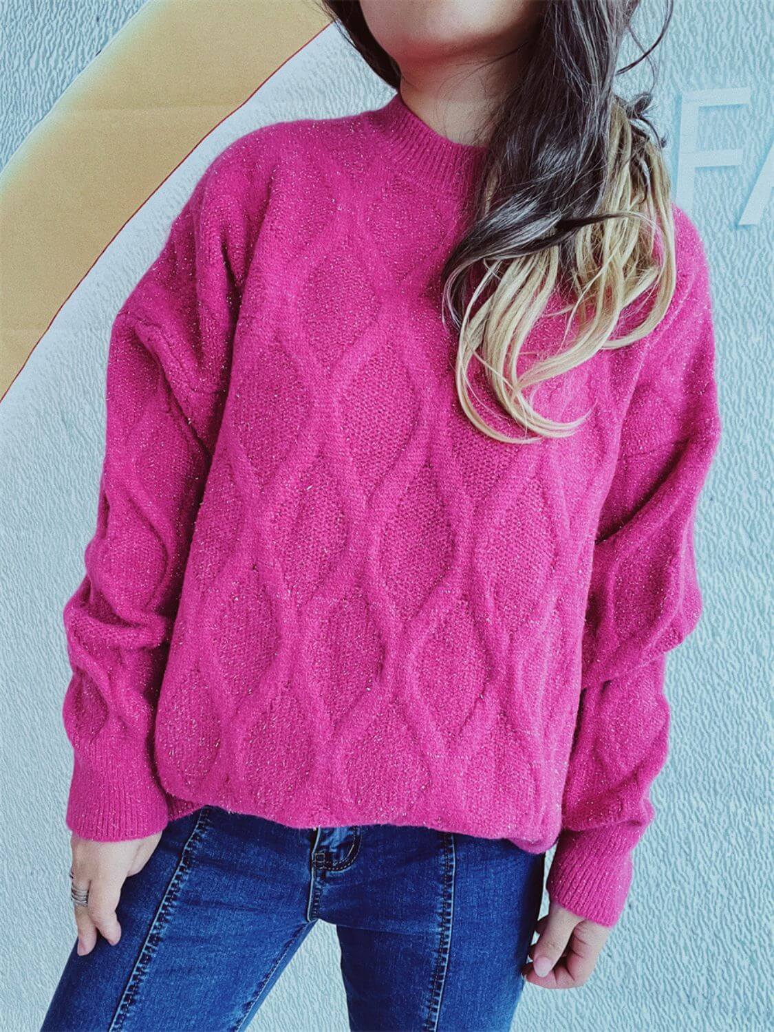 Woman wearing Bella Road Diamond Round Neck Long Sleeve Sweater in pink with unique diamond pattern, paired with blue jeans.