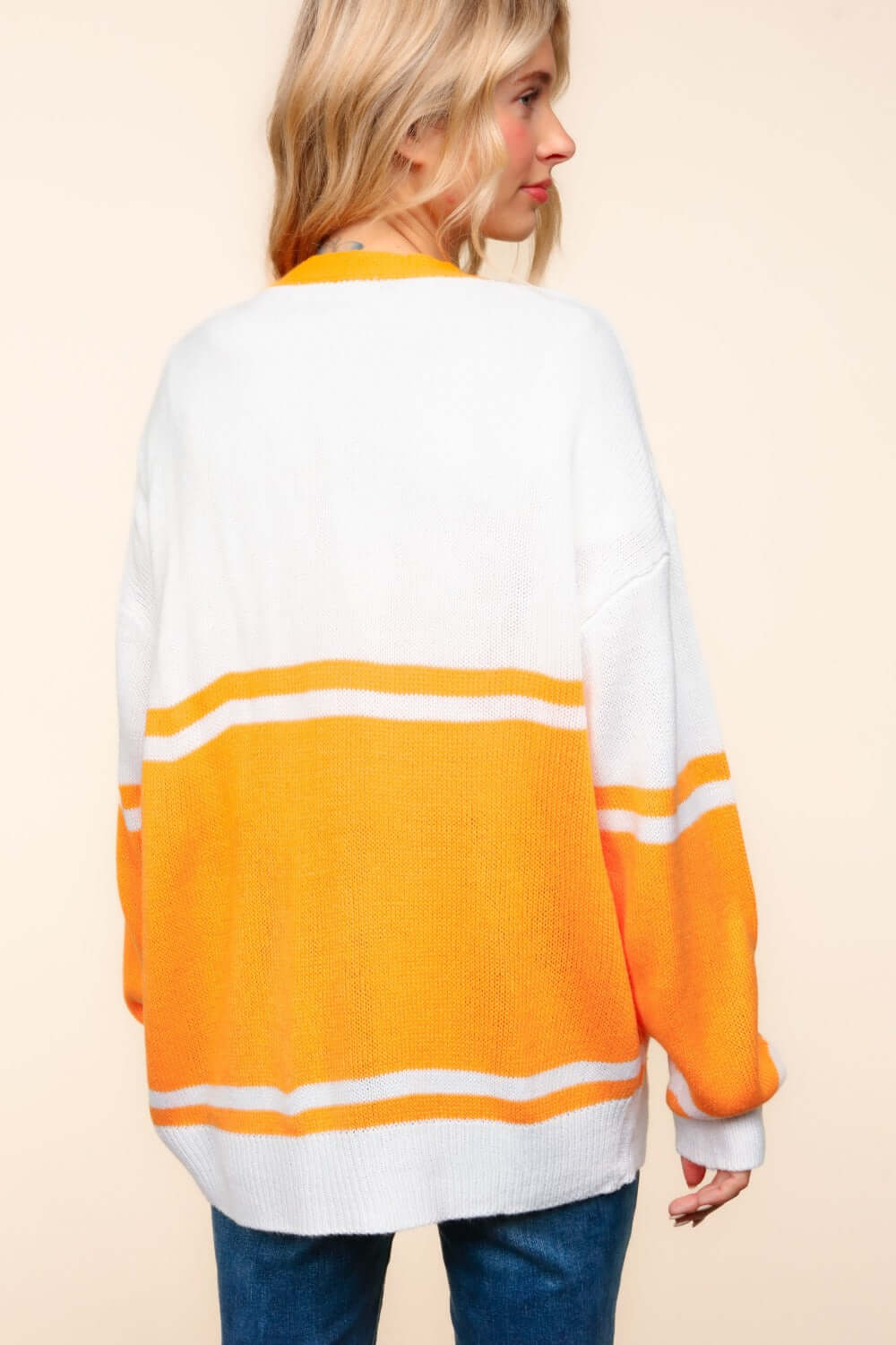 Woman wearing a loose-fitting, long-sleeve white and yellow striped cardigan, showcasing the back view.