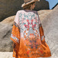 Woman wearing Bella Road Swim printed open front cover-up in vibrant colors at the beach, accessorized with a hat.