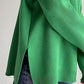 Cozy green side slit turtleneck sweater with dropped shoulders paired with jeans for a stylish and relaxed look.