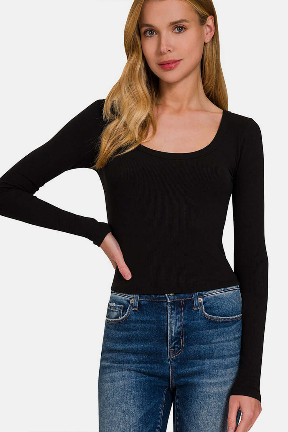 Woman wearing a black scoop neck long sleeve t-shirt paired with blue jeans.