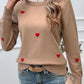 Woman wearing Devine Lace Detail Heart Long Sleeve Sweater in beige with red heart accents and jeans, casual chic style.