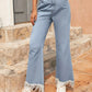 Woman wearing Bella Road light wash bootcut jeans with raw hem and pockets, styled with a trendy crop top and sneakers.