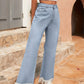 Woman in light wash bootcut jeans with raw hem and fringe, paired with a crop top, showcasing a stylish summer look.