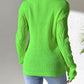 Woman wearing vibrant green openwork long sleeve sweater with jeans, showcasing stylish design and cozy texture.