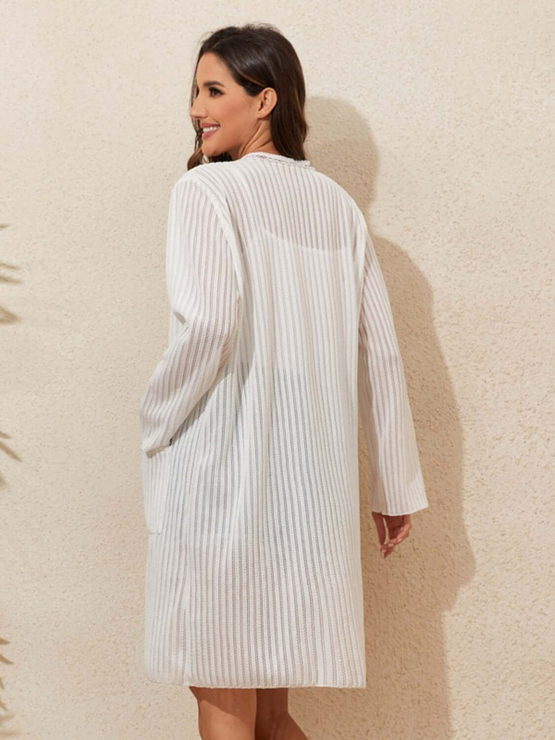 Woman wearing Lace Detail Open Front Long Sleeve Cover-Up in white, showcasing back view with sheer fabric and long sleeves.